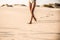 Legs of a young black woman walking in the sand in a desert dune