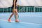 Legs of young girl in a closed tennis court with ball and racket