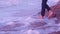 Legs of a young girl walking on earthen stone, beach, waves with foam at sunrise