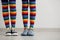 Legs of young lesbian couple in rainbow stockings standing against white wall