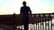 Legs of a young man move in the rays of a splendid sunset on a bridge in slo-mo