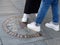 Legs of young people step on zero kilometre sign in Puerta del Sol square in Madrid, Spain