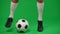 Legs of young professional footballer dribbling ball at chromakey background. Unrecognizable Caucasian sportsman