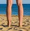 Legs of young sunburnt woman. Standing on seashore.