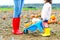 Legs of young woman and her little kid girl daugher in rainboots. Woman in red gum boots, child in yellow shoes. On