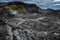 Leirhnjukur old black lava field with fumes coming from ground and blue sky in Iceland, overcast day in summer , film effect with