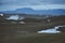 Leirhnjukur old black lava field with snow and colorful stones and smoke coming from ground and blue sky in Iceland, overcast day