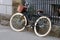 A leisure bike with a brown basket is parked near a metal fence.