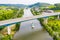 A leisure boat under high bridge where A13 motorway meets 8 highway over Moselle river. Aerial view of Schengen town center.