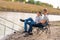 Leisure and people concept. Happy friends with fishing rods on pier by lakeside