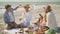 leisure, summer olidays, eating, people at picnic and food concept - happy friends having breakfast at summer beach