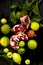 Lemon on a branch and limes. chopped grenade. on a black background. dark photo. water drops. wet fruit