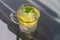 Lemon cooling drink mojito with ice in a glass with green mint leaves