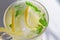 Lemon cooling drink mojito with ice in a glass with green mint leaves