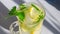 Lemon cooling drink mojito with ice in a glass with green mint leaves