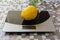Lemon on digital kitchen scale on table with oilcloth