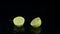 Lemon falls into the water and breaks up into two parts. Black background. Slow motion