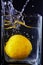 Lemon fell into a glass jar with water. Black background