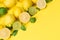 Lemon and green lime with sliced slices and citrus fruit leaves lie in the corner of the yellow background
