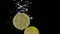 Lemon halves falling into water with air bubbles in slow motion