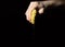 lemon with leaking juice squeezed in hand of man on black background