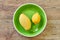 lemon and mango on a green plate on a wooden tabletop