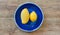 lemon and mango of yellow on a blue plate on a wooden tabletop