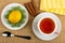 Lemon, marmalades in plate, cinnamon, napkin, cup of tea on saucer, spoon on mat. Top view