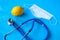 Lemon, medical mask and stethoscope on a blue background