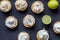Lemon meringue tarts on black background - top view photo of limes and lime meringues