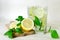 Lemon mint detox water. Home-made lemonade with mint, lemon and ice in glasses. Wooden board, sliced lemon and mint leaves