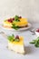 Lemon mousse vanilla cheesecake with lemon curd decorated by lemon and lime slices, frozen raspberry and mint.