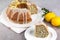 Lemon poppy seed Bundt Cake with icing and in a plate and a slice on a gray table