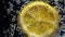 Lemon slice submerged in carbonated water with bubbles