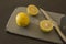 Lemon with slices and knife on grey cutting board