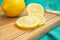 Lemon and slices of lemon on a wooden cutting board on a background of turquoise fabric