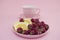 Lemon slices and raspberries in a pink plate on a pink background. Flat lay of tropical summer. Nutrition concept.