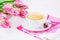 Lemon tea, chocolates heart, pink magenta tulips flowers on white wooden background