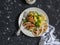 Lemon thyme baked chicken, potatoes and green peas on a white plate on a dark background.