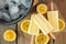 Lemon yogurt popsicles with lemon slices and rustic wood background