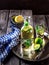 Lemonade in bottle and two glasses on vintage metal tray. Wooden background.