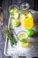 Lemonade in bottle and two glasses on vintage metal tray. Wooden background.