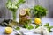 Lemonade with fresh lemons and green leaves of mint and currant in a glass jug on a gray background. Refreshing vitamin drinks