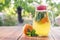 Lemonade pitcher with orange, mint and ice on garden table. Homemade orange lemonade with mint