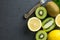 Lemons and kiwis fruits are on top of black kitchen table.