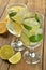 Lemons and limes in a glass with water on brown background