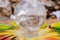 Lemurian Clear Quartz Sphere crystal magical orb in the middle of a circle made of colorful feathers.