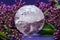 Lemurian Clear Quartz Sphere crystal magical orb surrounded by purple lilac flower.