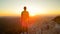 LENS FLARE: Athletic man stands on top of the hill and observes the sunrise.