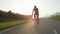 LENS FLARE: Athletic young sportsman pedals down an empty sunlit asphalt road.